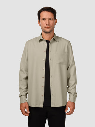 En mand iført en Effortless-skjorte i farven Stone Beige over en sort T-shirt.