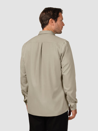 En mand set bagfra, iført en Effortless-skjorte i farven Stone Beige og sorte bukser.