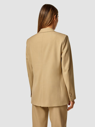 En person set bagfra, iført en lysebrun Essential Blazer Caramel i dansk design.