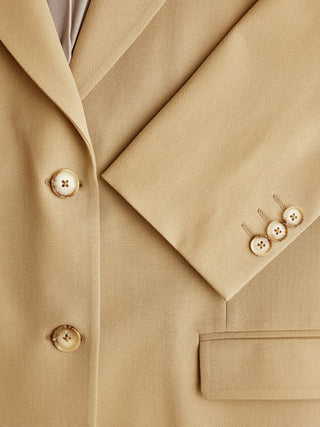 Nærbillede af en lysebrun Essential Blazer Caramel med knapdetaljer foran og på ærmerne i klassisk dansk design.