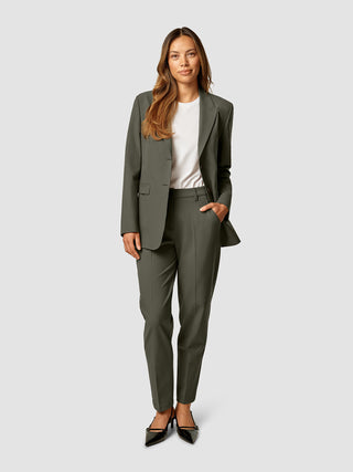 En kvinde iført en hvid T-shirt og et buksesæt fra Essential Blazer i farven Dark Olive.