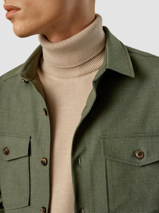 En person har en beige rullekravesweater på under en opknappet Essential Overshirt i farven Nightfall Green Melange.