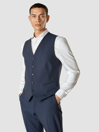 En mand iført en Essential Vest Navy Melange over en stryget hvid skjorte.