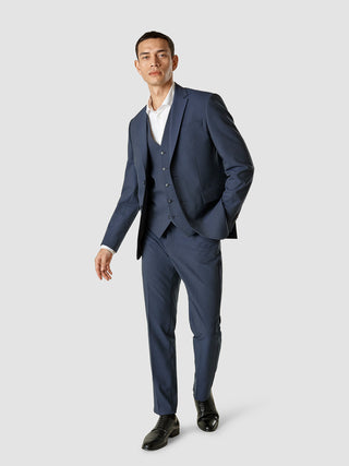 En mand iført en hvid skjorte og en Essential Vest Navy Melange over et marineblåt jakkesæt.