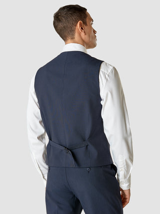 Bagfra-billede af en mand i en hvid skjorte og en marineblå Essential Vest Navy Melange med en justerbar rygrem.