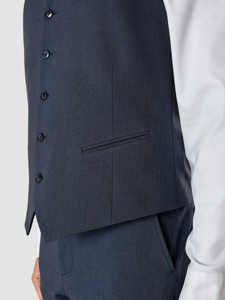 En Essential-vest i navy melange, båret over en hvid skjorte.