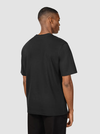 En mand set bagfra, iført en sort Heavy Box Fit-T-shirt.