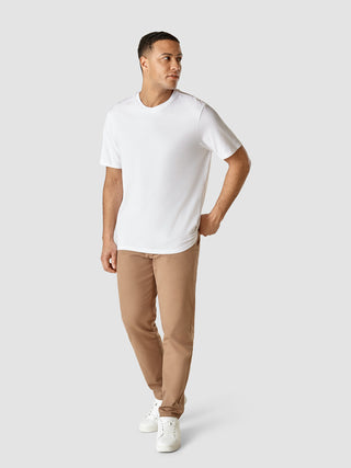 En mand iført en Supima T-shirt i Box Fit Legacy White, beige bukser og hvide sneakers.