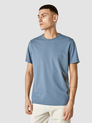 En mand iført en Supima-T-shirt i farven Blue Mirage med dansk design.