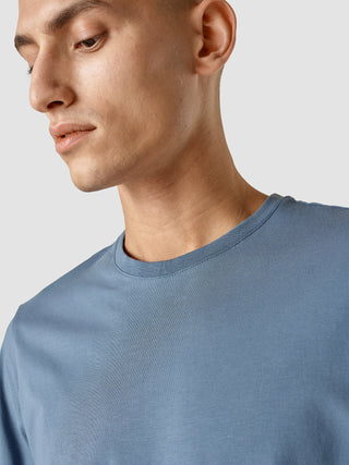 En mand iført en Supima T-shirt med rund hals i farven Blue Mirage.
