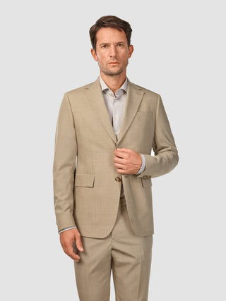 En mand iført en Tech Wool Suit Sand-jakke og en lys skjorte med knapper.