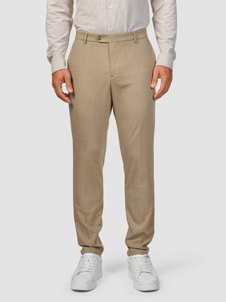 En mand iført et Tech Wool-jakkesæt i farven Sand, beige bukser og hvide sneakers.
