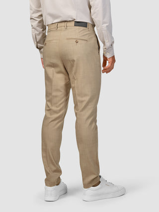 Bagfra-billede af en person, der bærer et Tech Wool Suit Sand-jakkesæt med en lys skjorte og hvide sneakers.
