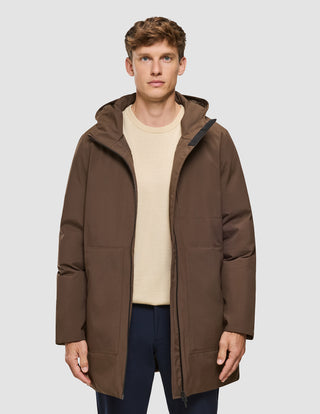 En mand iført en brune Utility-jakke over en beige sweater og mørke bukser.