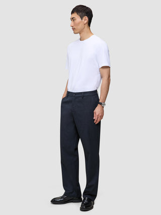 En mand i en hvid T-shirt og Atelier Pants Relaxed Dark Navy, stylet i minimalistisk dansk design.