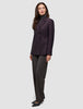 En kvinde iført en Avira-blazer i farven Burgundy Berry over en grå rullekravebluse og mørke bukser i dansk stil.
