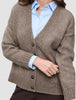 En kvinde har en tyk, blød uldstrikket cardigan i farven taupe-melange på over en lyseblå skjorte med krave.
