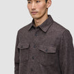 En person, der bærer en brun, langærmet Double Layer Wool Overshirt med knapper og to brystlommer.