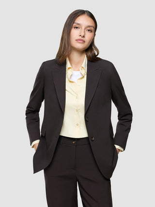 En kvinde iført en Women Ease Blazer i farven Mocha Melange over en lysegul skjorte med knapper.