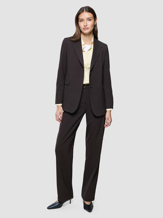 En kvinde iført en Women Ease-blazer i farven Mocha Melange og tilhørende bukser over en lysegul skjorte med knapper.