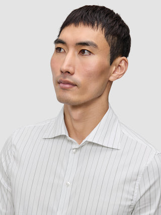 En mand iført en Elevated Shirt Regular Light Grey Striped, en hvid skjorte med tynde grå lodrette striber.