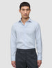 En mand iført en Elevated Shirt Slim Classic Blue Striped-skjorte med knapper og mørkegrå bukser.