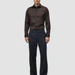 En mand har en mørkebrun Elevated Shirt Slim i Pima-bomuld på sammen med mørke bukser og fine sko.