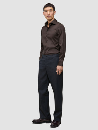 En mand iført en Elevated Shirt Slim i mørkebrun Pima-bomuld og antracitgrå bukser.