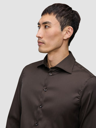 En mand iført en mørkebrun Elevated Shirt Slim-skjorte med knapper.