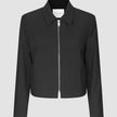 Essential Short Zip Jacket Black, en minimalistisk sort jakke med en sølvfarvet lynlås i fuld længde foran.