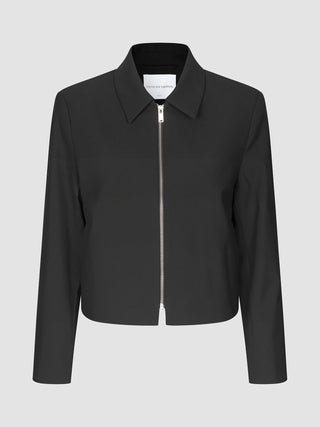Essential Short Zip Jacket Black, en minimalistisk sort jakke med en sølvfarvet lynlås i fuld længde foran.