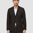 En mand iført en Motion Blazer Regular Cognac i mørkebrun over en hvid skjorte med knapper.