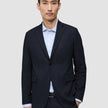 En mand bærer en Motion Blazer Regular i farven Midnight Blue over en lyseblå skjorte med knapper, hvilket fremhæver det rene danske design.