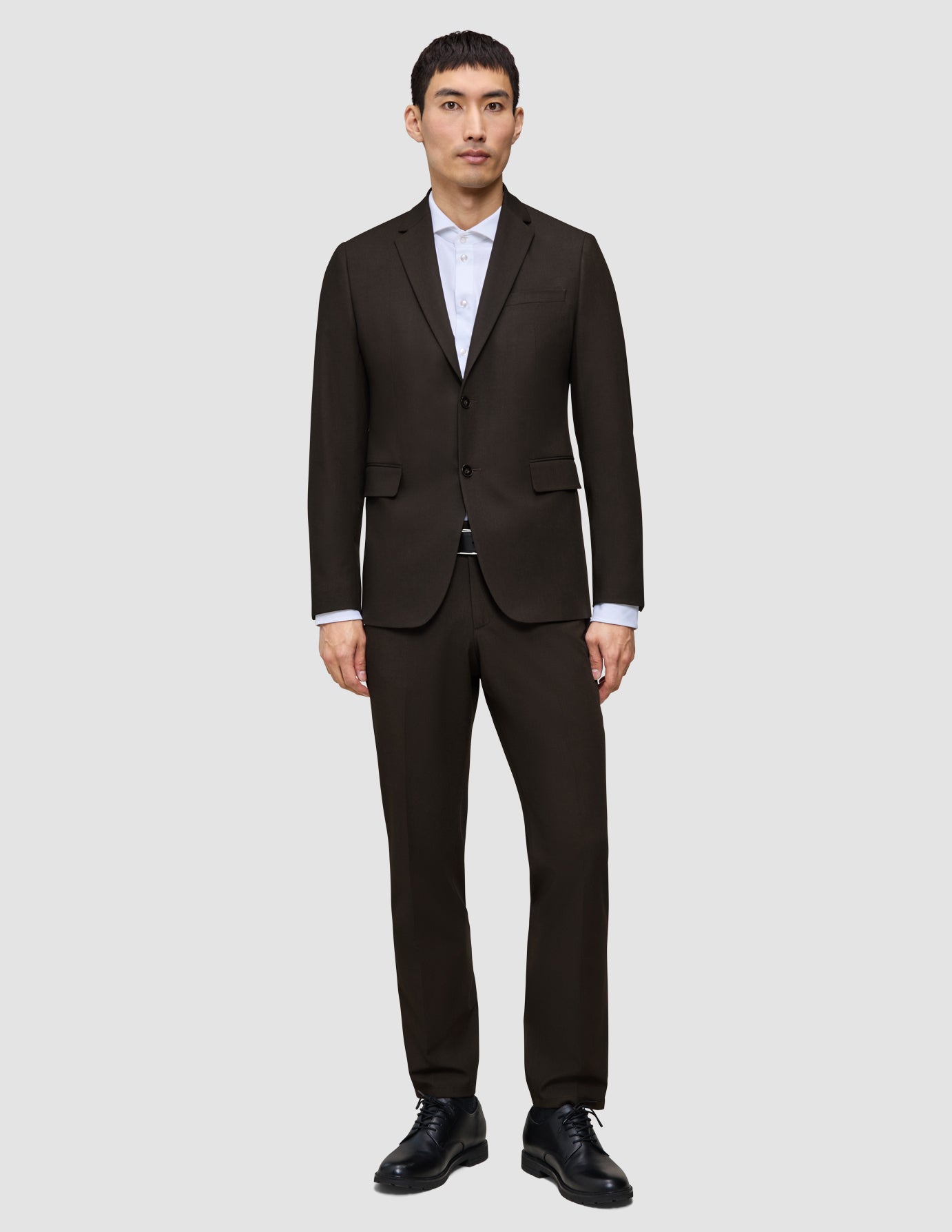 En mand iført en mørkebrun Motion Blazer Slim Cognac, en hvid skjorte og sorte herresko.