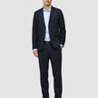 En mand iført en Motion Blazer Slim i farven Midnight Blue, en lyseblå skjorte og mørke læderloafers.