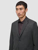 En mand iført en Motion Blazer Slim i farven Pepper Grey over en mørk skjorte med knapper.