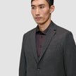 En mand iført en Motion Blazer Slim i farven Pepper Grey over en mørk skjorte med knapper.