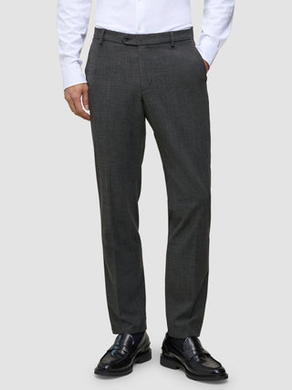 En person har grå Motion Suit-bukser i farven Regular Pepper Grey på, en hvid skjorte med knapper og sorte læderloafers.