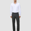 En mand i en hvid skjorte med knapper og et par Motion Suit-bukser i farven Regular Pepper Grey.