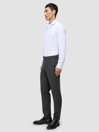 En mand i en hvid skjorte og Motion Suit-bukser i Regular Pepper Grey står set i profil og er indbegrebet af det rene danske design.
