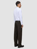 Set fra siden: en mand i en hvid skjorte med knapper og Motion Suit-bukser i modellen Relaxed i farven Cognac.