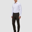 En mand iført en hvid skjorte med knapper, Motion Suit Pants Slim Cognac og sorte støvler.