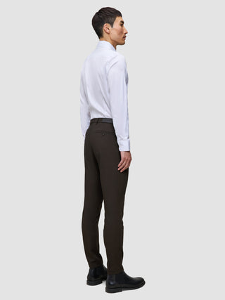 En mand set fra siden, iført en hvid skjorte med knapper og et par Motion Suit-bukser i Slim-pasform i farven Cognac med dansk design.
