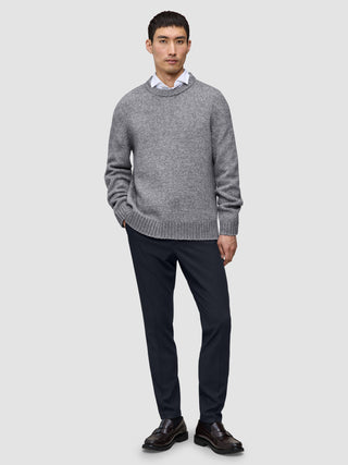 En mand har en grå trøje, en hvid skjorte, Motion Suit-bukser i slim fit i midnatsblå og mørke læderloafers på.