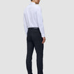 En mand set bagfra iført en hvid skjorte med knapper, Motion Suit-bukser i slim fit i midnatsblå og mørke læderloafers.