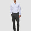En mand i en hvid skjorte med knapper og et par Motion Suit-bukser i farven Slim Pepper Grey samt sorte loafers.
