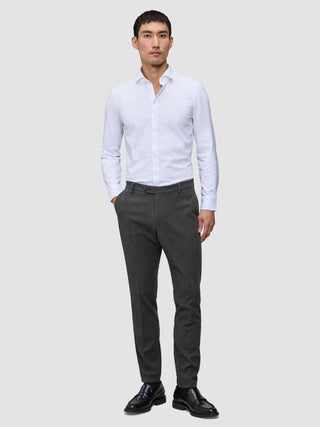 En mand i en hvid skjorte med knapper og et par Motion Suit-bukser i farven Slim Pepper Grey samt sorte loafers.