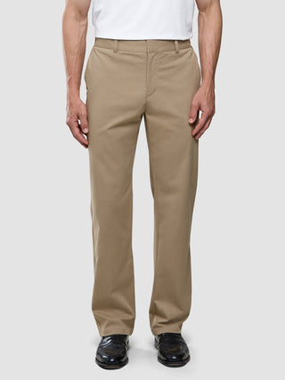 En person iført en hvid T-shirt, Refine Cotton Pants i Relaxed Fit i farven Sand og sorte lædersko.