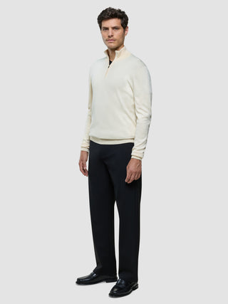 En mand iført en Seamless Core Knit Half Zip Birchwood, sorte bukser og sorte loafers.