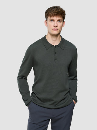 En mand iført en mørkegrøn Seamless Core Knit langærmet polo i farven »Green Night«.